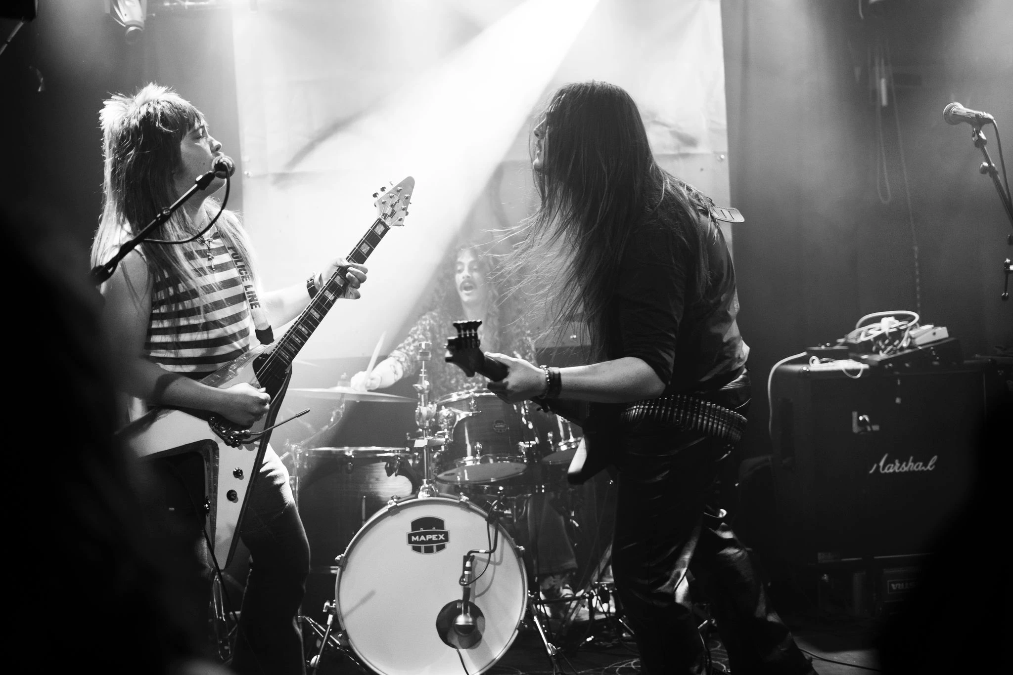 Bandfoto von Manta in schwarz/weiß.
Die drei Männer mit langen Haaren sind auf der Bühne. 
Der Gitarrist und der Bassist stehen zueinandergewandt und schauen sich an, der Gitarrist singt zusätzlich in ein Mikrofon. Zwischen den beiden sieht man den Schlagzeuger