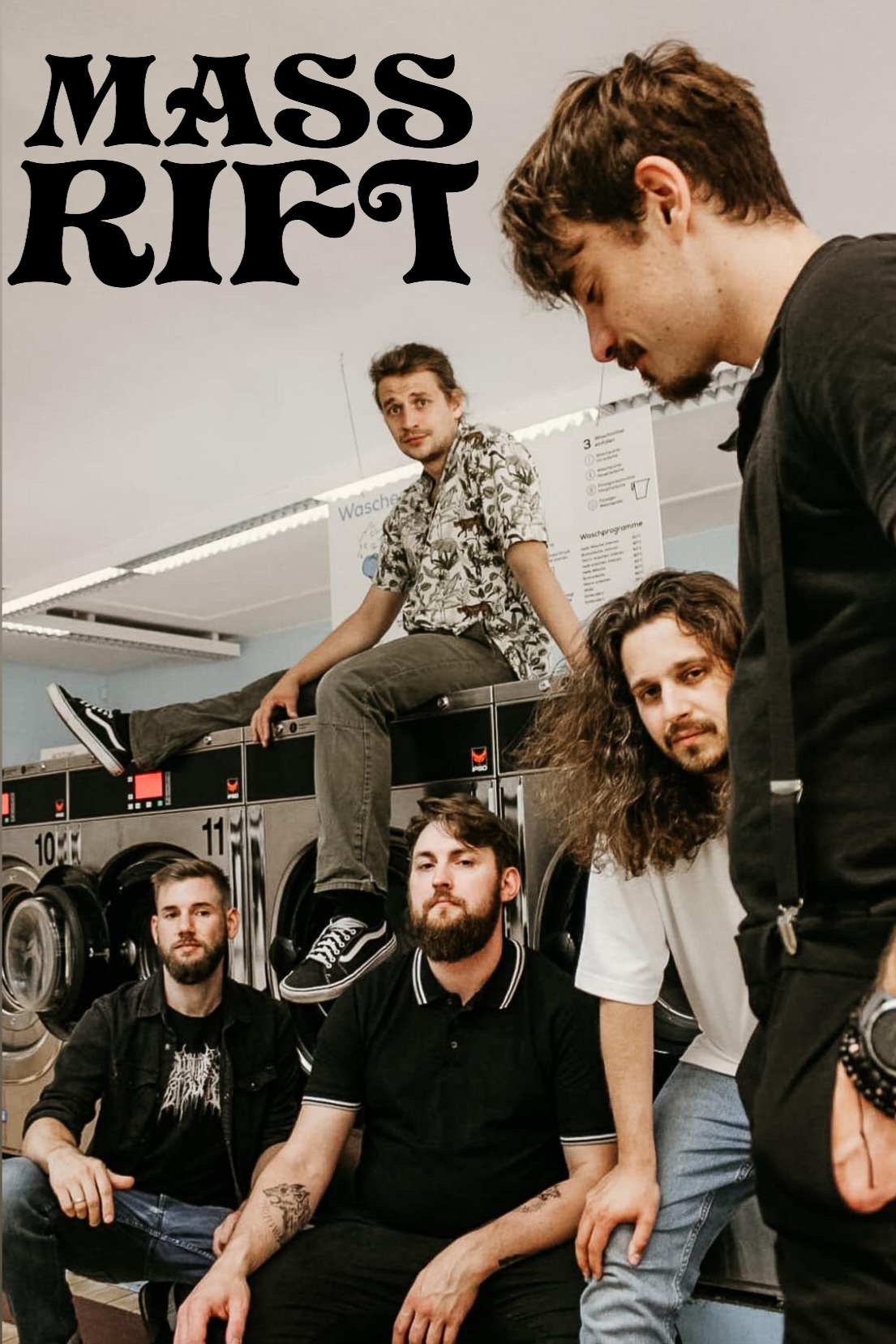 Band photo with Logo of Mass Rift.
Five men in a laundromat.
Two people squat in front of the large washing machines, one leans against them, one stands in front of them and one sits on one of the machines.
At the top left you can see the band logo. “Mass Rift” in black, bold, slightly squiggly letters.