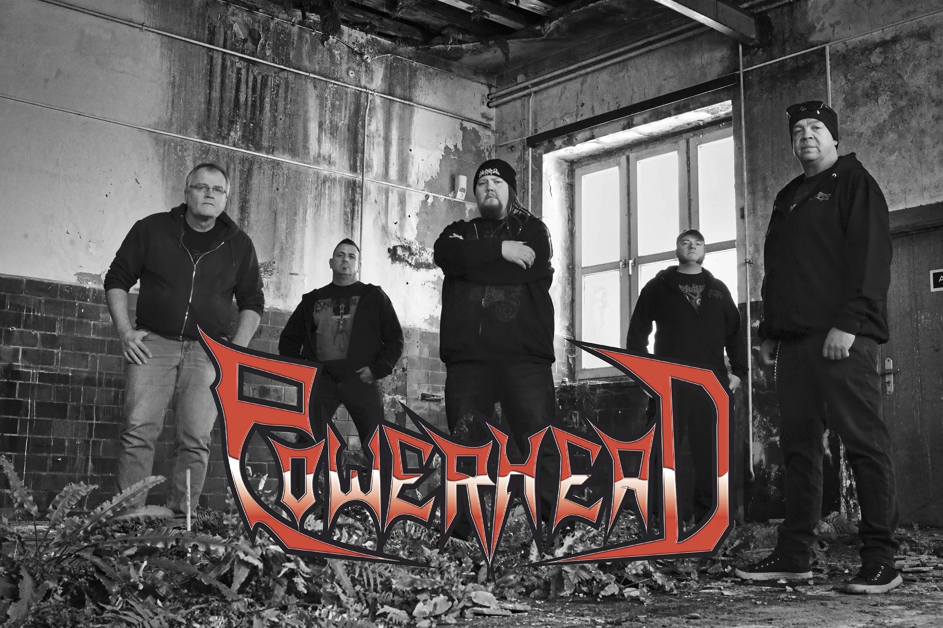 Fünf Männer stehen in einer verlassenen Lagerhalle.
Unten im Bild das Powerhead Logo 