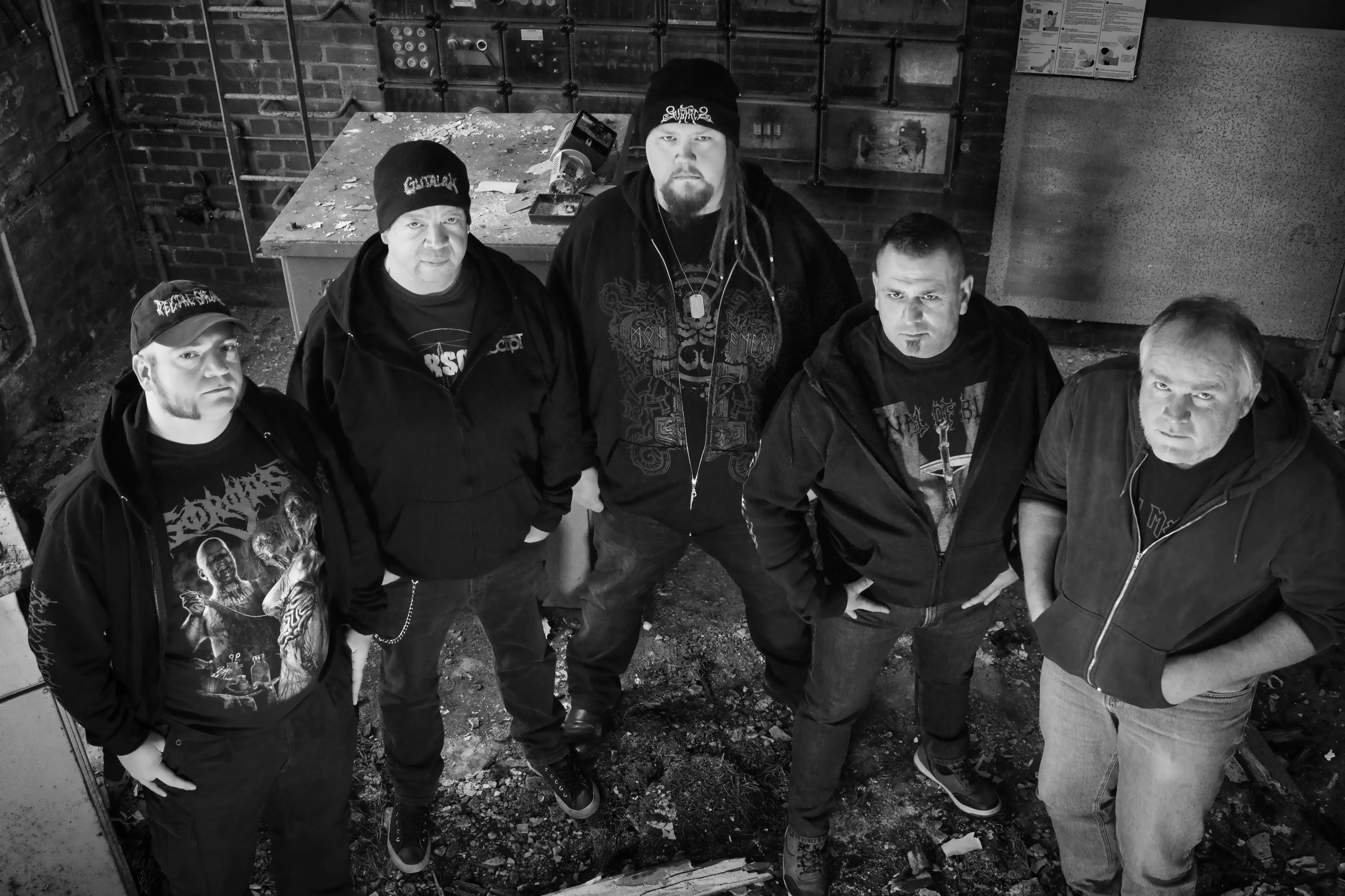 Five men in an abandoned warehouse room looking up towards the camera.